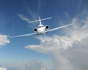 A white airplane flying through the sky with clouds.